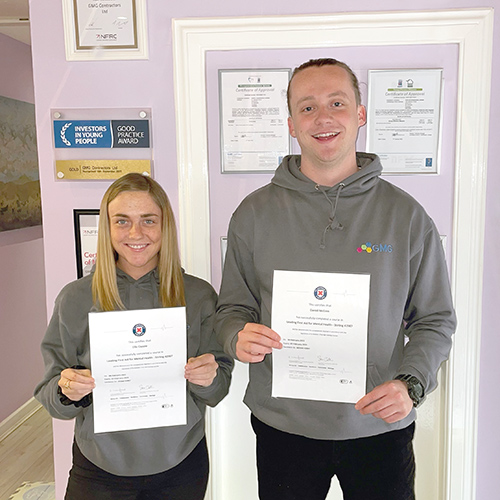 An image of Daniel McGinn and Elis Cappie holding certificates after qualifying as Mental Health First Aiders